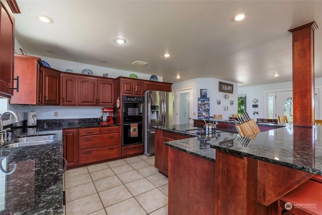 kitchen featuring sink, stainless steel fridge with ice dispenser, dark stone countertops, double oven, and kitchen peninsula