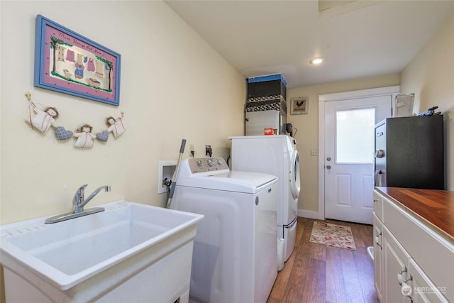 clothes washing area with washer and dryer, sink, cabinets, and dark wood-type flooring