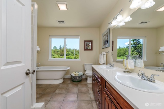 bathroom with a washtub, vanity, tile patterned floors, and toilet