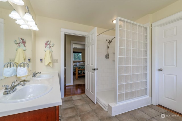 bathroom with tile patterned flooring, a tile shower, and vanity