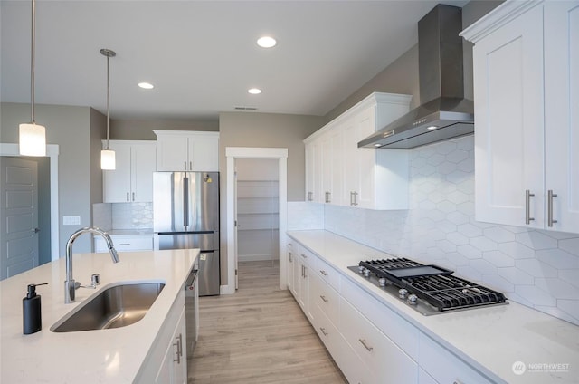 kitchen featuring stainless steel appliances, white cabinetry, sink, and wall chimney range hood