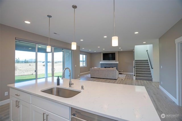 kitchen featuring light stone countertops, sink, hanging light fixtures, and white cabinets