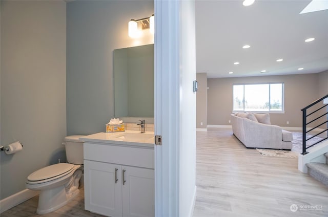 bathroom with hardwood / wood-style flooring, vanity, and toilet