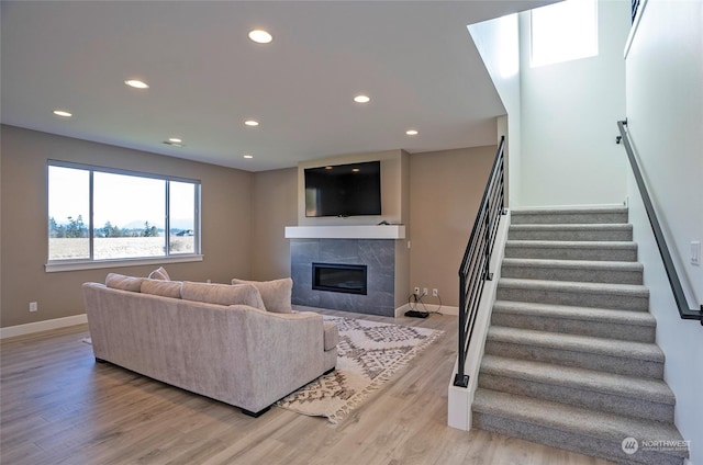 living room featuring a tile fireplace and light hardwood / wood-style flooring