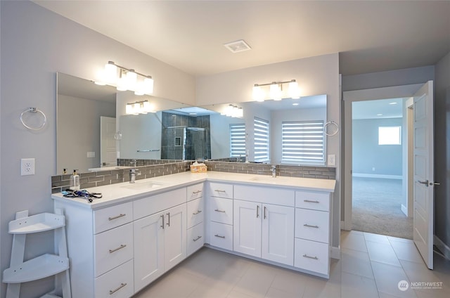 bathroom with tile patterned flooring, vanity, a shower with shower door, and decorative backsplash