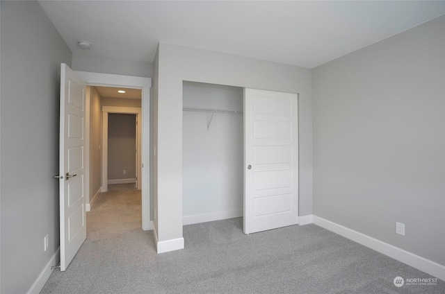 unfurnished bedroom featuring light colored carpet and a closet