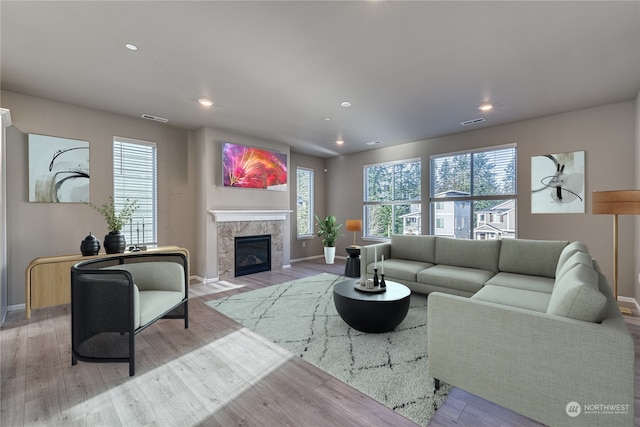 living room featuring a tile fireplace and light hardwood / wood-style flooring