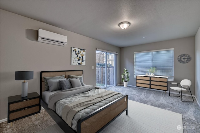 bedroom with a textured ceiling, carpet floors, and a wall unit AC