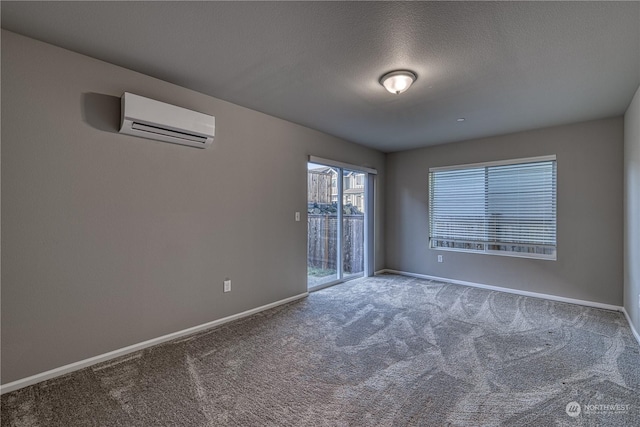 spare room with a textured ceiling, carpet floors, and an AC wall unit