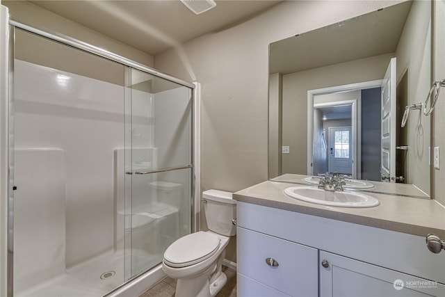 bathroom featuring vanity, a shower with shower door, and toilet