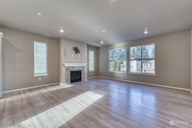 unfurnished living room featuring a high end fireplace and light wood-type flooring