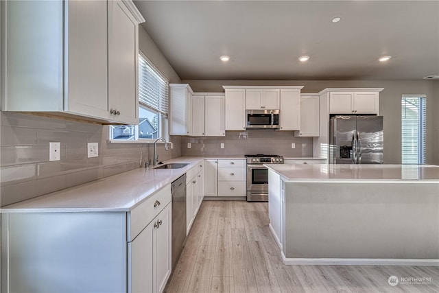 kitchen featuring appliances with stainless steel finishes, light hardwood / wood-style floors, white cabinetry, and sink