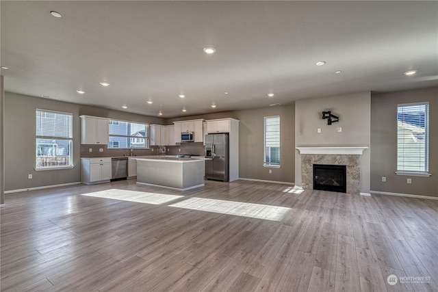 kitchen featuring sink, a center island, appliances with stainless steel finishes, white cabinets, and light wood-type flooring