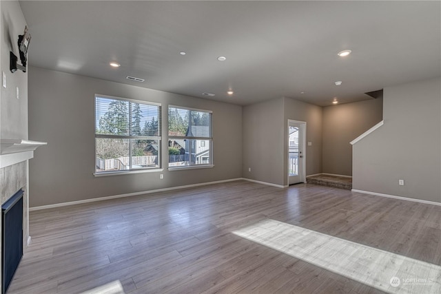 unfurnished living room with a fireplace and light wood-type flooring