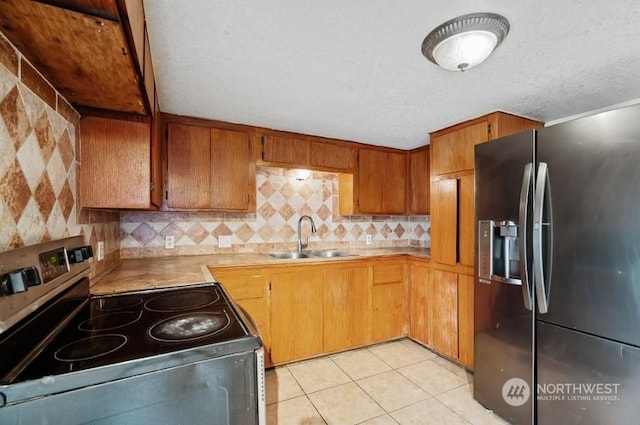 319 4th Ave, Mabton, WA 98935 - kitchen featuring sink, tasteful backsplash, a textured ceiling, light tile patterned floors, and appliances with stainless steel finishes