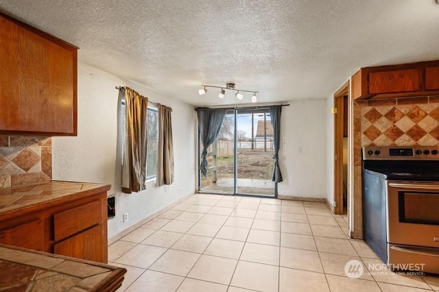 319 4th Ave, Mabton, WA 98935 - kitchen with tasteful backsplash, electric range, tile counters, and a textured ceiling