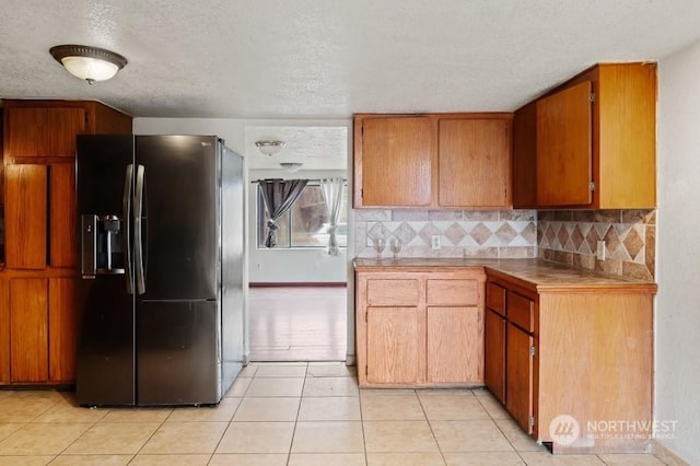 319 4th Ave, Mabton, WA 98935 - kitchen featuring backsplash, a textured ceiling, light tile patterned floors, and stainless steel refrigerator with ice dispenser