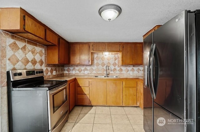 319 4th Ave, Mabton, WA 98935 - kitchen with sink, black fridge, stainless steel electric stove, decorative backsplash, and light tile patterned flooring
