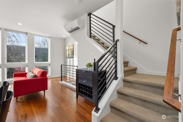 stairs featuring hardwood / wood-style floors and a wall mounted air conditioner