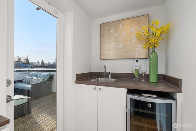 bar featuring wine cooler, white cabinetry, sink, and hardwood / wood-style flooring