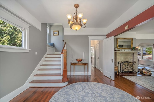 stairs with plenty of natural light, hardwood / wood-style floors, and a brick fireplace