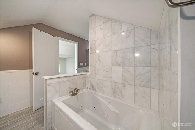 bathroom featuring a bathing tub, lofted ceiling, and tile walls