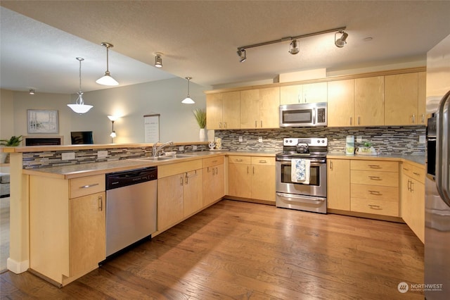 kitchen featuring kitchen peninsula, appliances with stainless steel finishes, light brown cabinets, and light hardwood / wood-style flooring