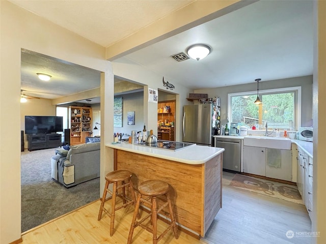 kitchen with sink, appliances with stainless steel finishes, light hardwood / wood-style floors, kitchen peninsula, and a breakfast bar area