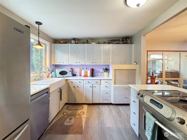 kitchen featuring pendant lighting, hardwood / wood-style flooring, appliances with stainless steel finishes, and sink