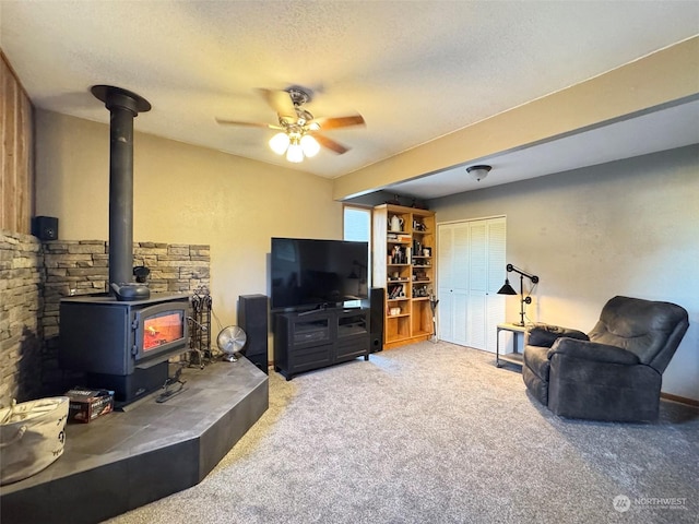 carpeted living room with ceiling fan, a wood stove, and a textured ceiling