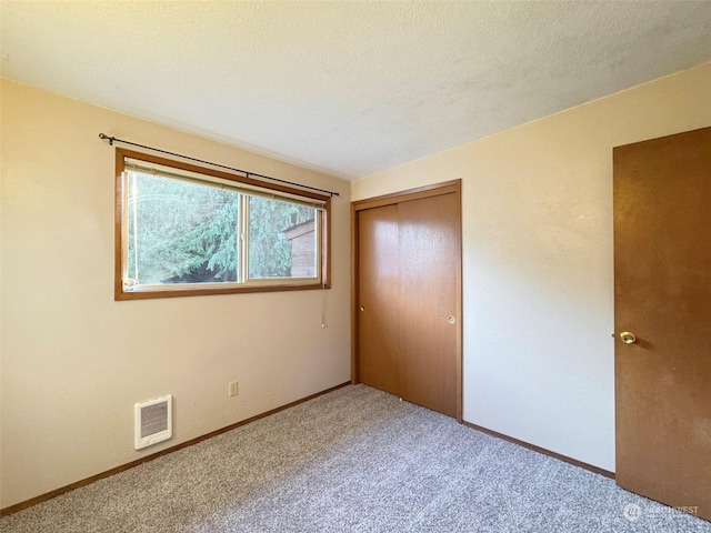 unfurnished bedroom featuring carpet, a textured ceiling, and a closet