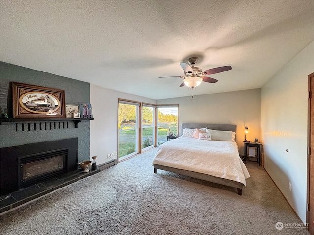 carpeted bedroom featuring access to outside, a tile fireplace, ceiling fan, and a textured ceiling