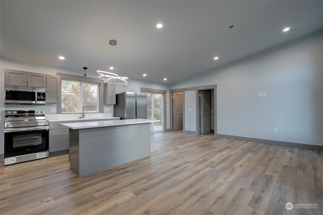 kitchen with lofted ceiling, a kitchen island, hanging light fixtures, gray cabinetry, and stainless steel appliances