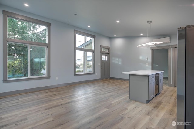 kitchen featuring a kitchen island, light hardwood / wood-style floors, hanging light fixtures, and gray cabinets