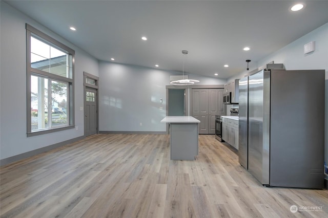 kitchen featuring stainless steel appliances, a healthy amount of sunlight, a kitchen island, pendant lighting, and light hardwood / wood-style flooring