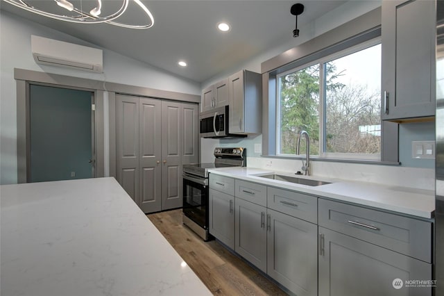 kitchen featuring an AC wall unit, appliances with stainless steel finishes, sink, gray cabinets, and vaulted ceiling