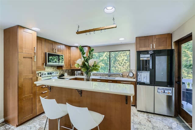 kitchen featuring a breakfast bar, a center island, sink, tasteful backsplash, and stainless steel appliances