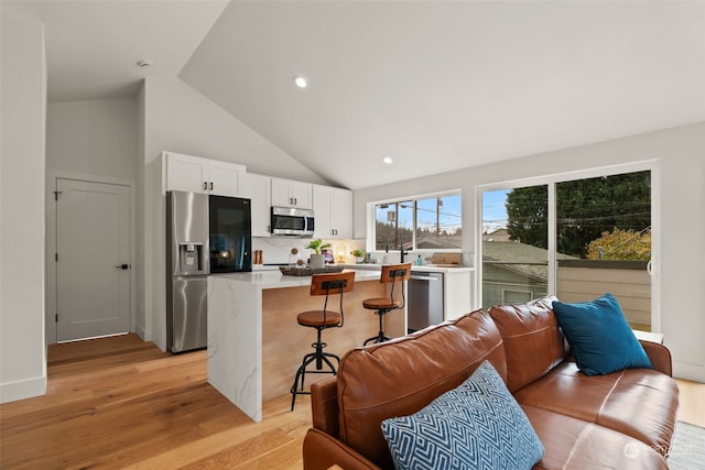 kitchen with white cabinets, a kitchen island, light hardwood / wood-style floors, and stainless steel appliances