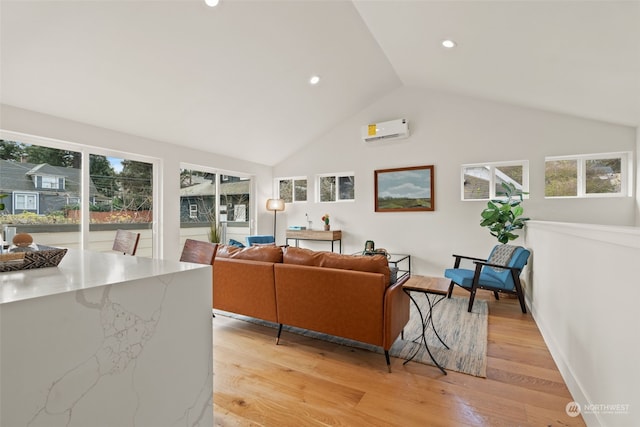 living room featuring vaulted ceiling, light hardwood / wood-style floors, an AC wall unit, and a wealth of natural light