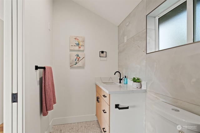 bathroom with tile patterned floors, vanity, toilet, and lofted ceiling