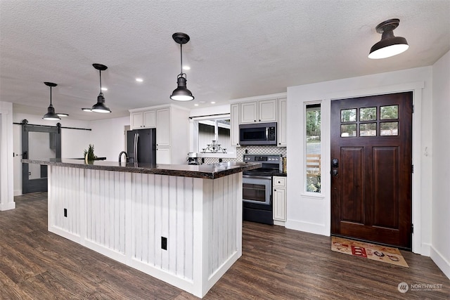 kitchen with a barn door, white cabinetry, dark wood-type flooring, and stainless steel appliances