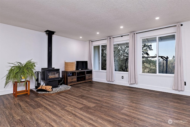 living room featuring a wood stove, dark wood-type flooring, and a textured ceiling