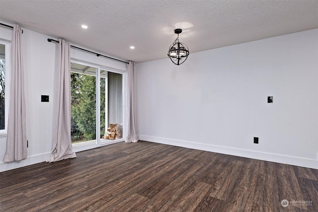 spare room with a textured ceiling, dark hardwood / wood-style floors, and a notable chandelier