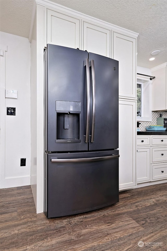 interior space with white cabinets, dark hardwood / wood-style floors, stainless steel fridge, and tasteful backsplash