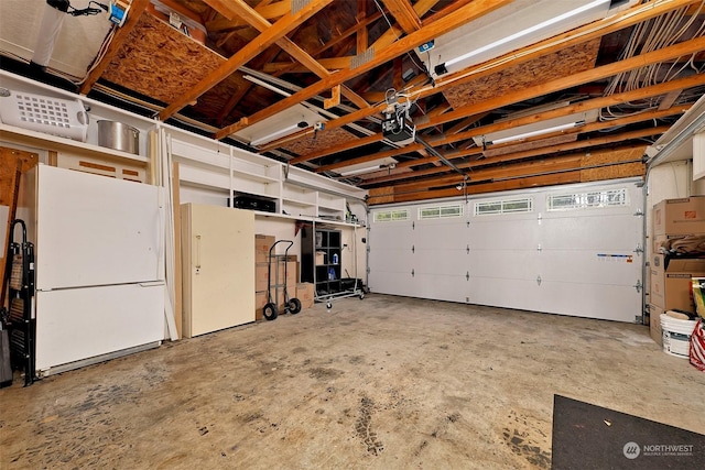 garage featuring white fridge and a garage door opener