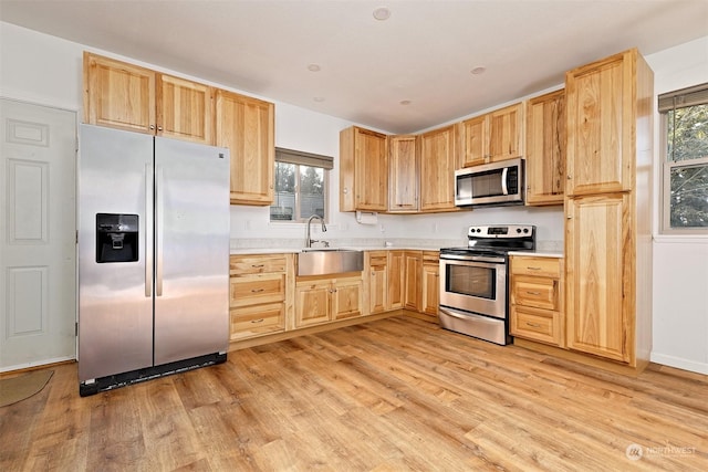 kitchen featuring sink, stainless steel appliances, light brown cabinetry, and light hardwood / wood-style flooring