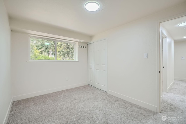 unfurnished bedroom with light carpet and a closet