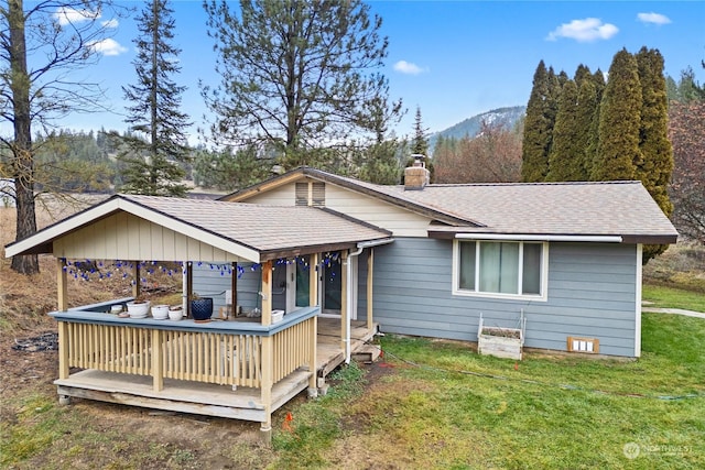 rear view of property with a deck with mountain view and a lawn