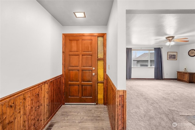 corridor featuring light hardwood / wood-style floors and wood walls