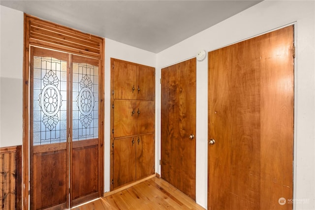 foyer entrance featuring light hardwood / wood-style floors and wooden walls